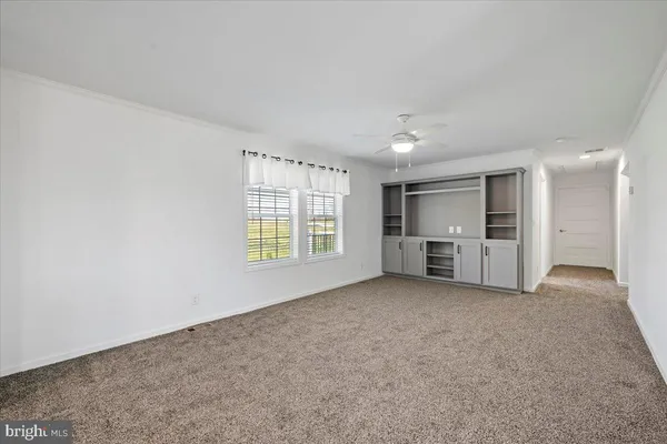 a view of an empty room with a window and kitchen