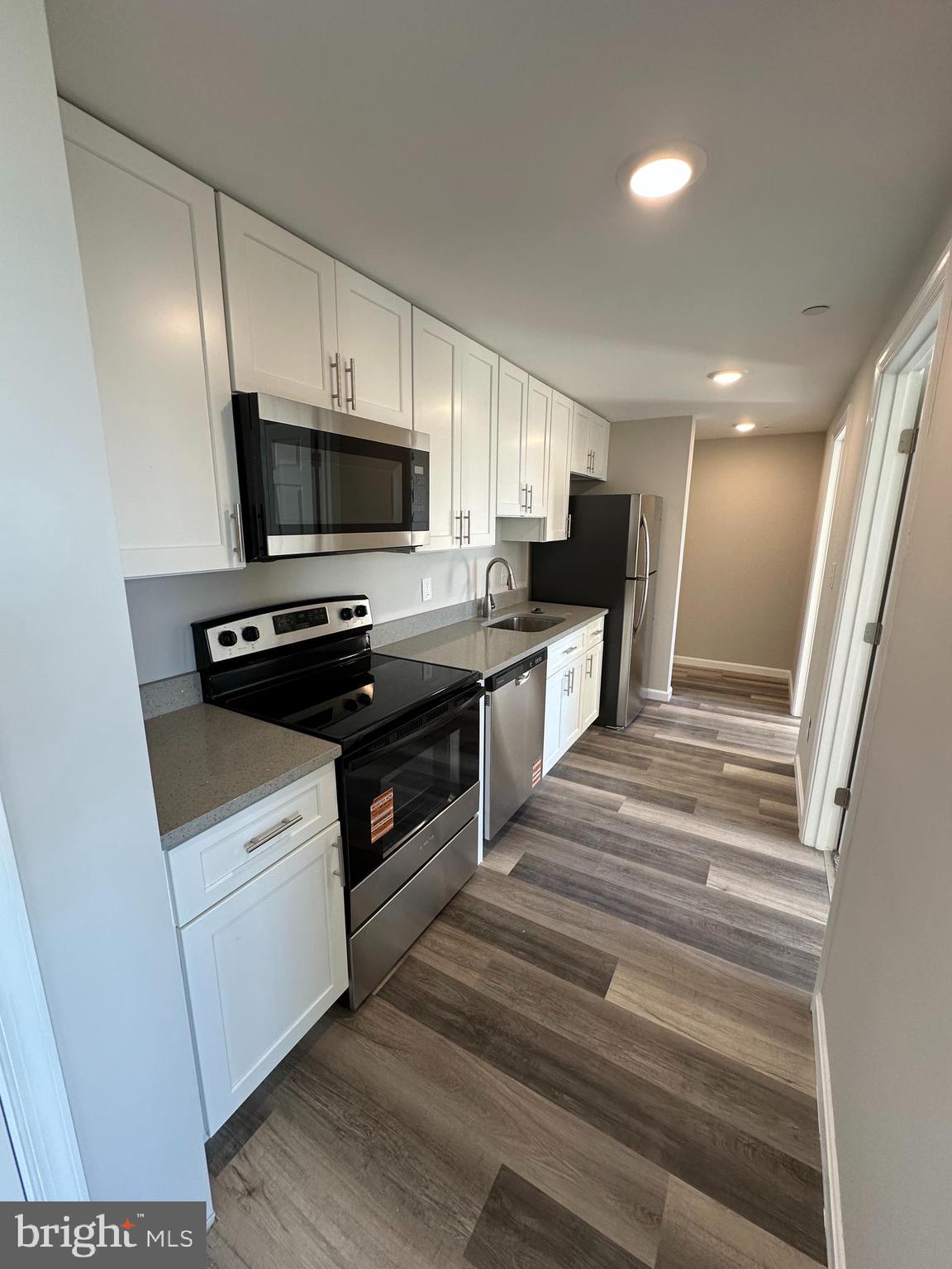 1812 H Place Northeast, Unit B02 Washington, DC 20002 - Photo 2 of 13 a kitchen with a stove a microwave and white cabinets