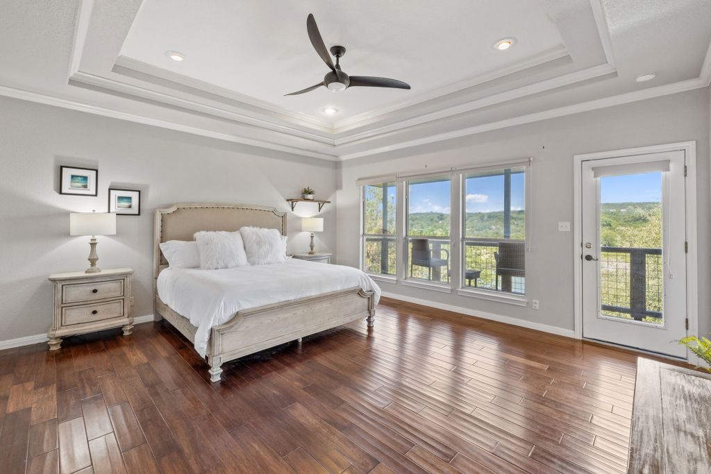 10800 Beach Road Leander, TX 78641 - Photo 17 of 39 Relax in this sun-filled bedroom, offering rich wood flooring and a private balcony with scenic outdoor views.