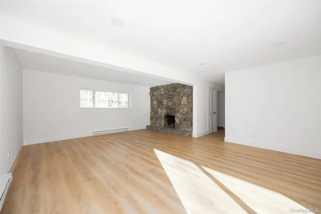 a view of empty room with wooden floor and fireplace