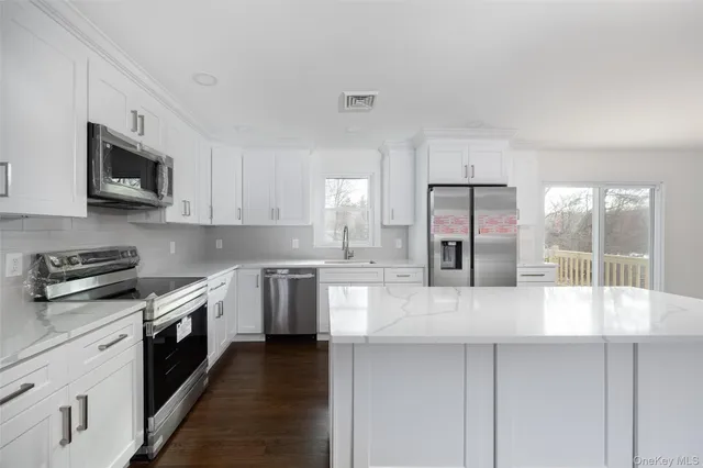 a large kitchen with stainless steel appliances granite countertop a stove a sink and a microwave