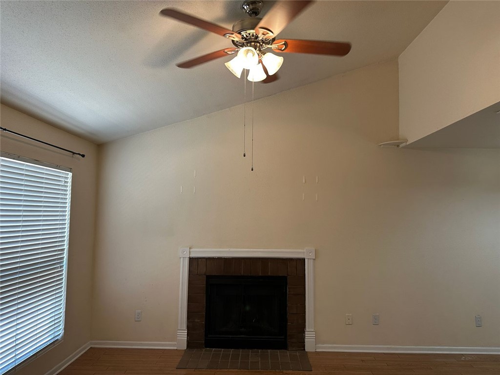 1501 Stallings Drive, Unit 52 College Station, TX 77840 - Photo 3 of 15 Unfurnished living room featuring dark wood-type flooring, a fireplace with raised hearth, and ceiling fan