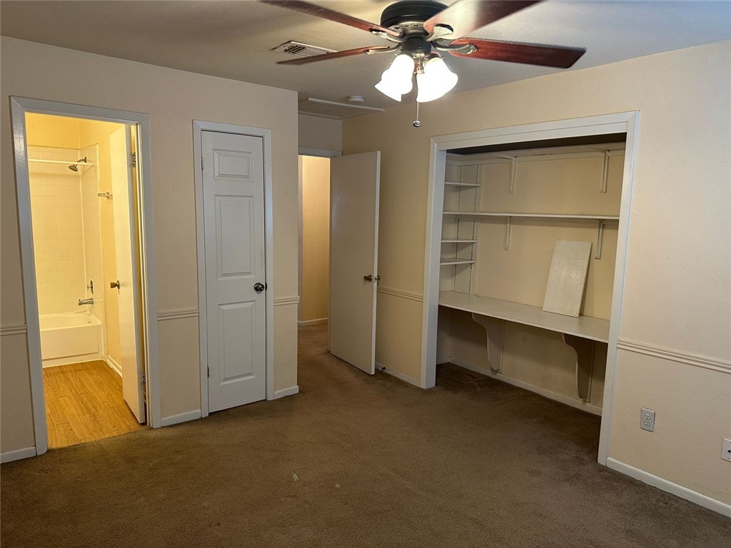 1501 Stallings Drive, Unit 52 College Station, TX 77840 - Photo 7 of 15 Unfurnished bedroom featuring dark carpet, ensuite bath, a ceiling fan, and a closet