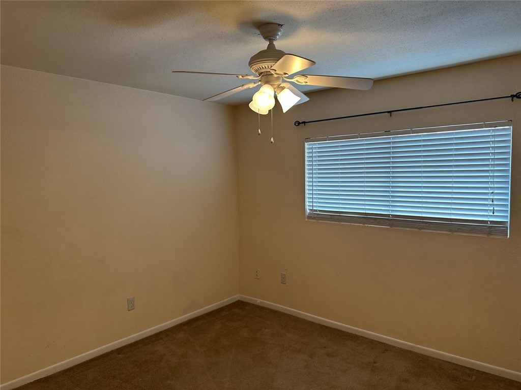 1501 Stallings Drive, Unit 52 College Station, TX 77840 - Photo 8 of 15 Unfurnished room with dark colored carpet, a ceiling fan, and a textured ceiling
