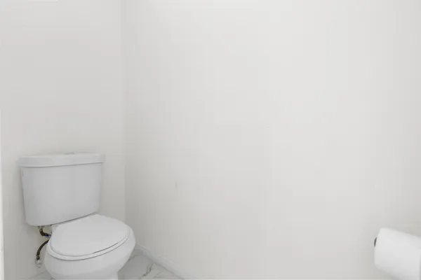 a white toilet sitting next to a white wall