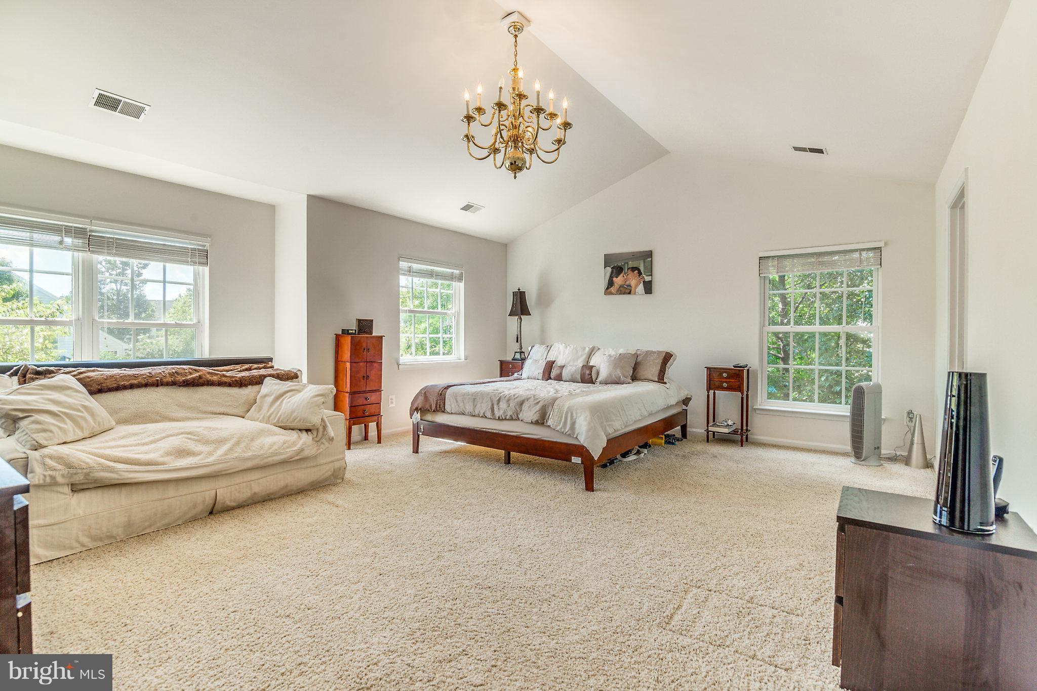 24806 Prairie Grass Drive Aldie, VA 20105 - Photo 15 of 30 a spacious bedroom with a bed a chandelier and large window