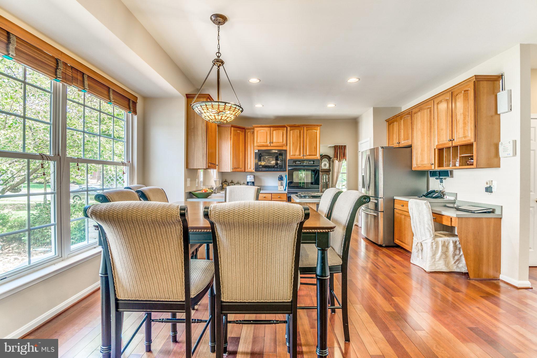 24806 Prairie Grass Drive Aldie, VA 20105 - Photo 7 of 30 a dining room with stainless steel appliances granite countertop a stove a sink a dining table and chairs with wooden floor