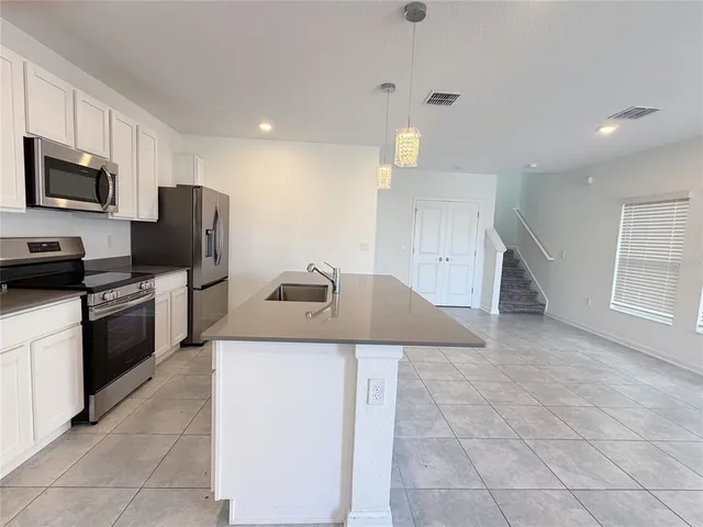 a large kitchen with stainless steel appliances a large counter top a sink a stove a refrigerator and cabinets