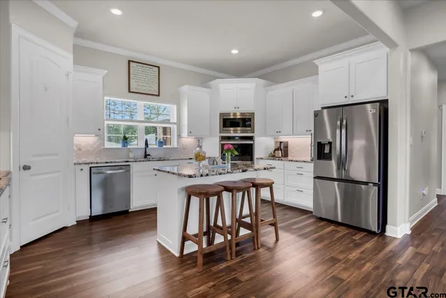 a kitchen with granite countertop cabinets stainless steel appliances and wooden floor