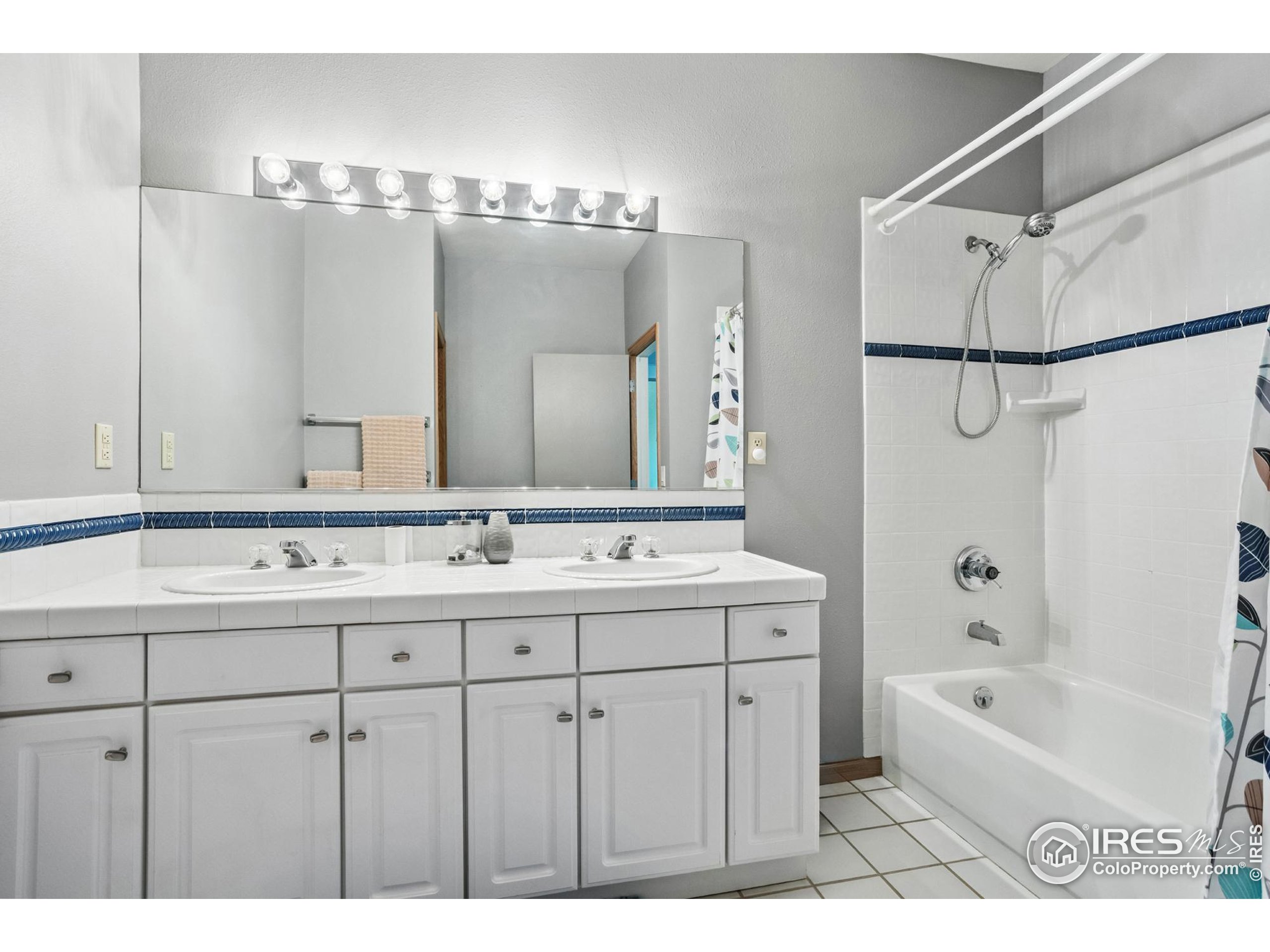 3310 Routt Street Wheat Ridge, CO 80033 - Photo 22 of 35 a bathroom with a double vanity sink a large mirror and a bathtub