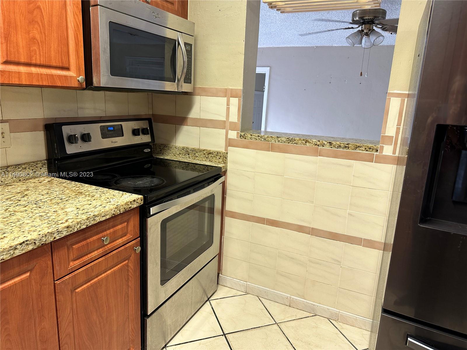 5643 Southwest 7th Street Miami, FL 33144 - Photo 17 of 25 a kitchen with stainless steel appliances granite countertop a stove a microwave and a sink
