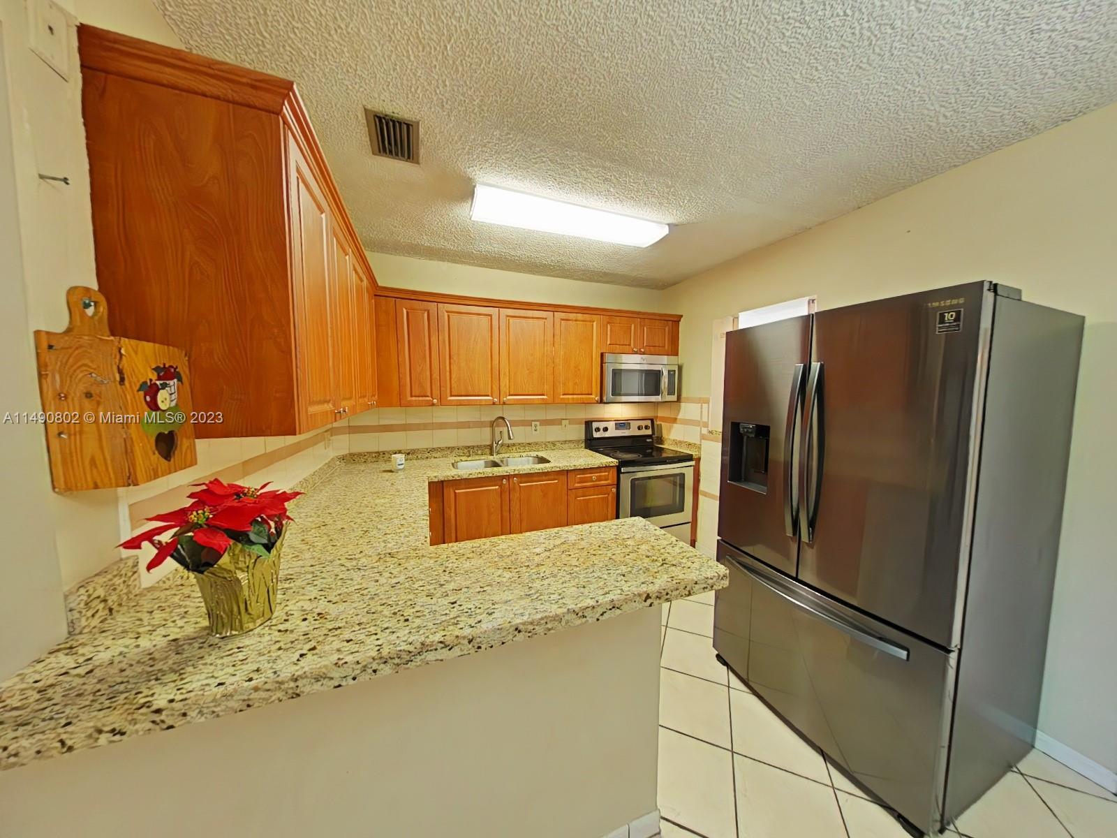 5643 Southwest 7th Street Miami, FL 33144 - Photo 3 of 25 a kitchen with granite countertop a refrigerator and a sink