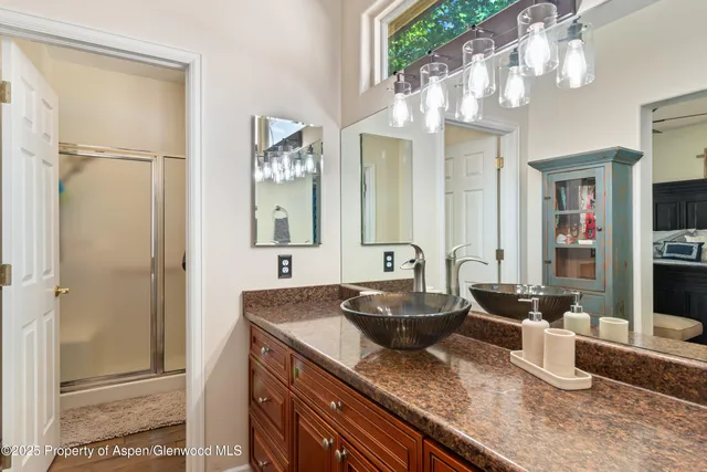 a spacious bathroom with a granite countertop sink a mirror and shower