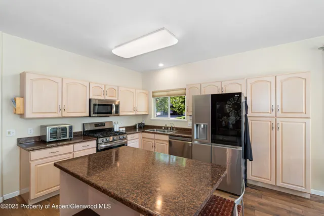 a kitchen with stainless steel appliances granite countertop a refrigerator a stove top oven a sink and dishwasher