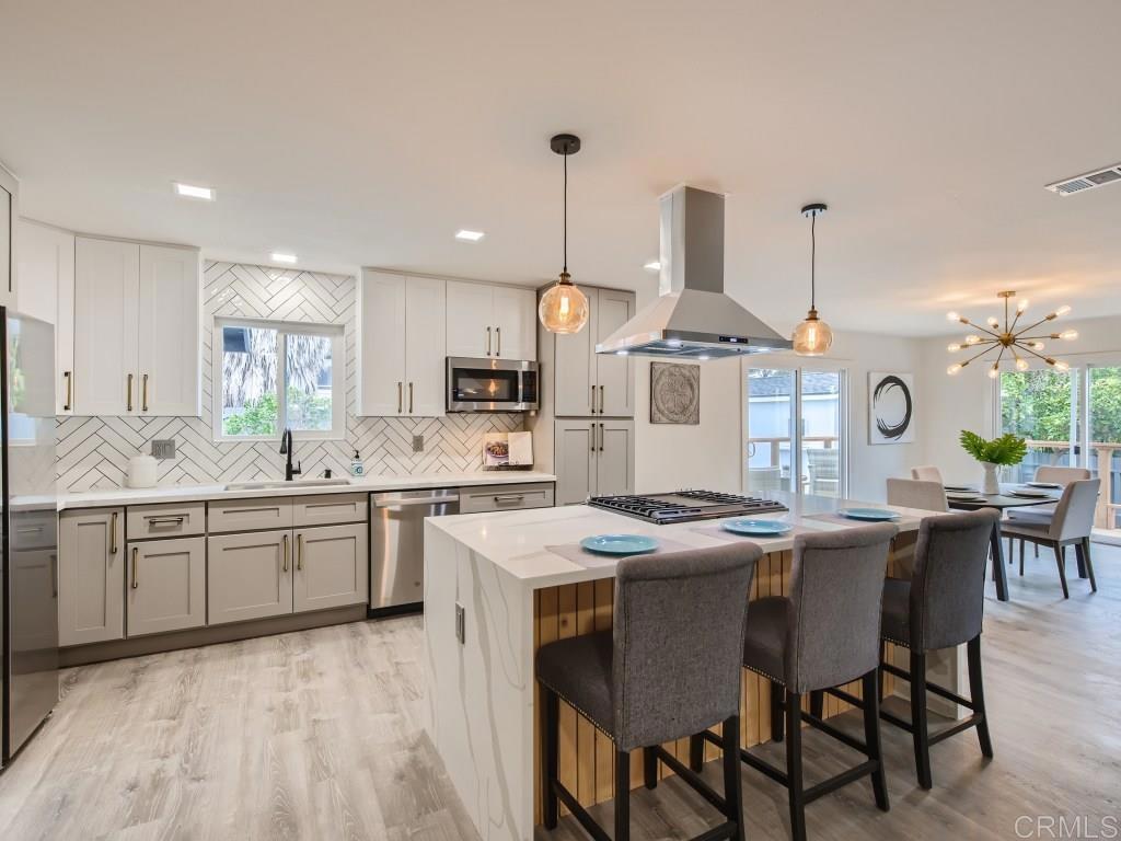a kitchen with granite countertop lots of white cabinets a dining table and chairs