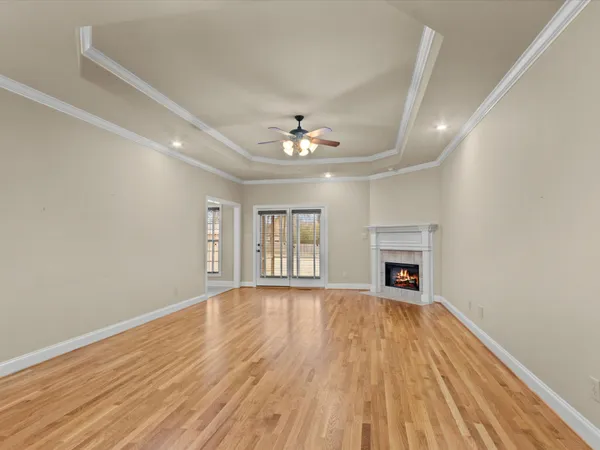 a view of an empty room with wooden floor fireplace and a window