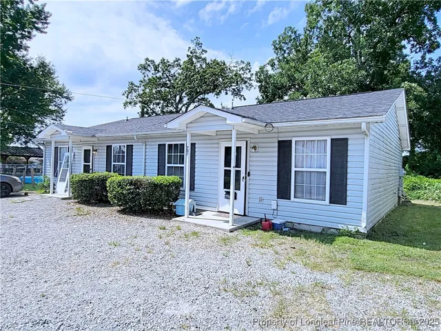 a view of a brick house with a large windows plants and large tree