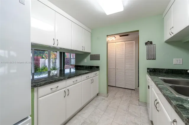 a kitchen with white cabinets a sink and stainless steel appliances