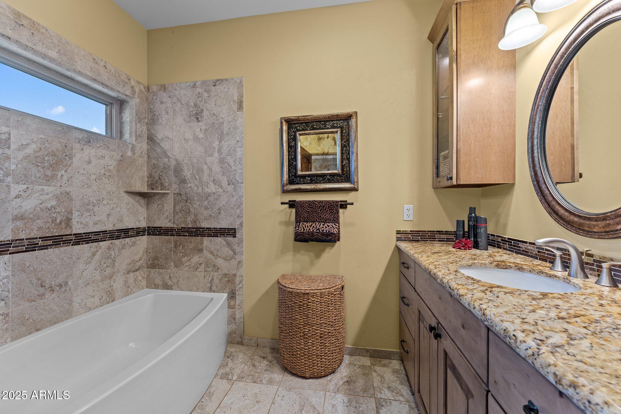 17789 West Peak View Road Surprise, AZ 85387 - Photo 29 of 69 a bathroom with a granite countertop sink a toilet and bathtub