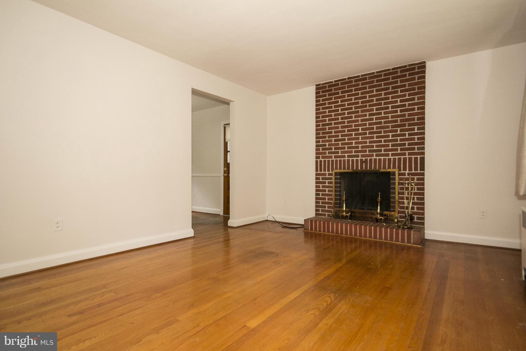 4113 Raleigh Road Baltimore, MD 21207 - Photo 5 of 23 a view of an empty room with wooden floor fireplace and a window