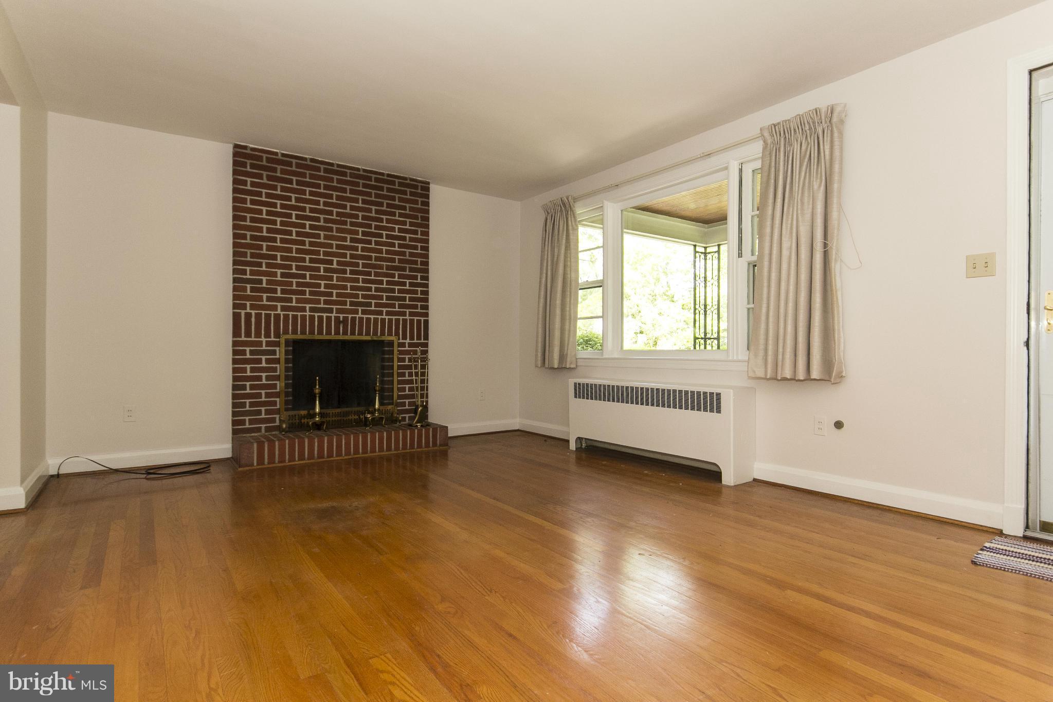 4113 Raleigh Road Baltimore, MD 21207 - Photo 6 of 23 an empty room with wooden floor fireplace and windows
