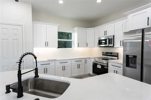 a kitchen with granite countertop a refrigerator stove and sink