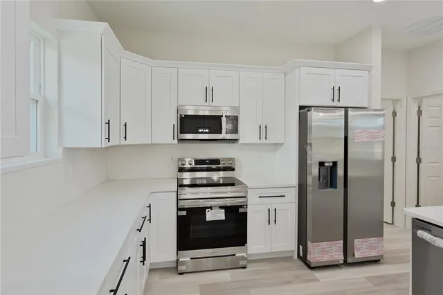 a kitchen with a refrigerator stove and white cabinets