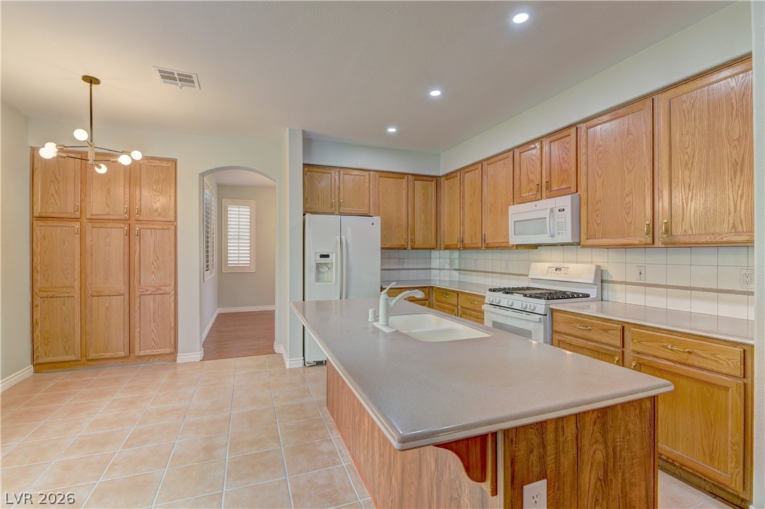 1813 Snow Spring Lane Las Vegas, NV 89134 - Photo 12 of 37 A well-equipped kitchen features ample cabinetry, a central island with sink, and tile flooring.