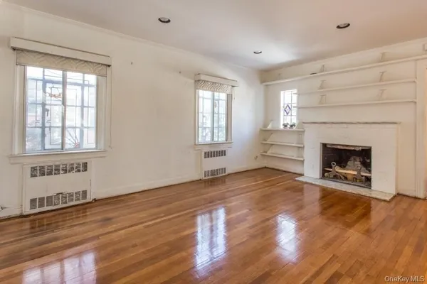 a view of empty room with wooden floor and fireplace