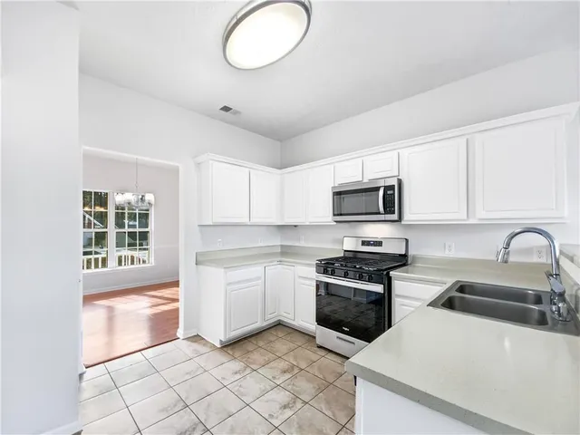 a kitchen with granite countertop a sink a stove top oven and cabinetry