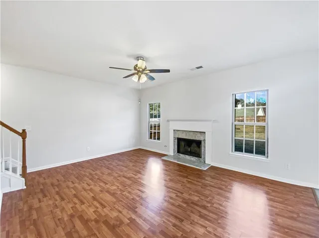a view of an empty room with wooden floor fireplace and a window