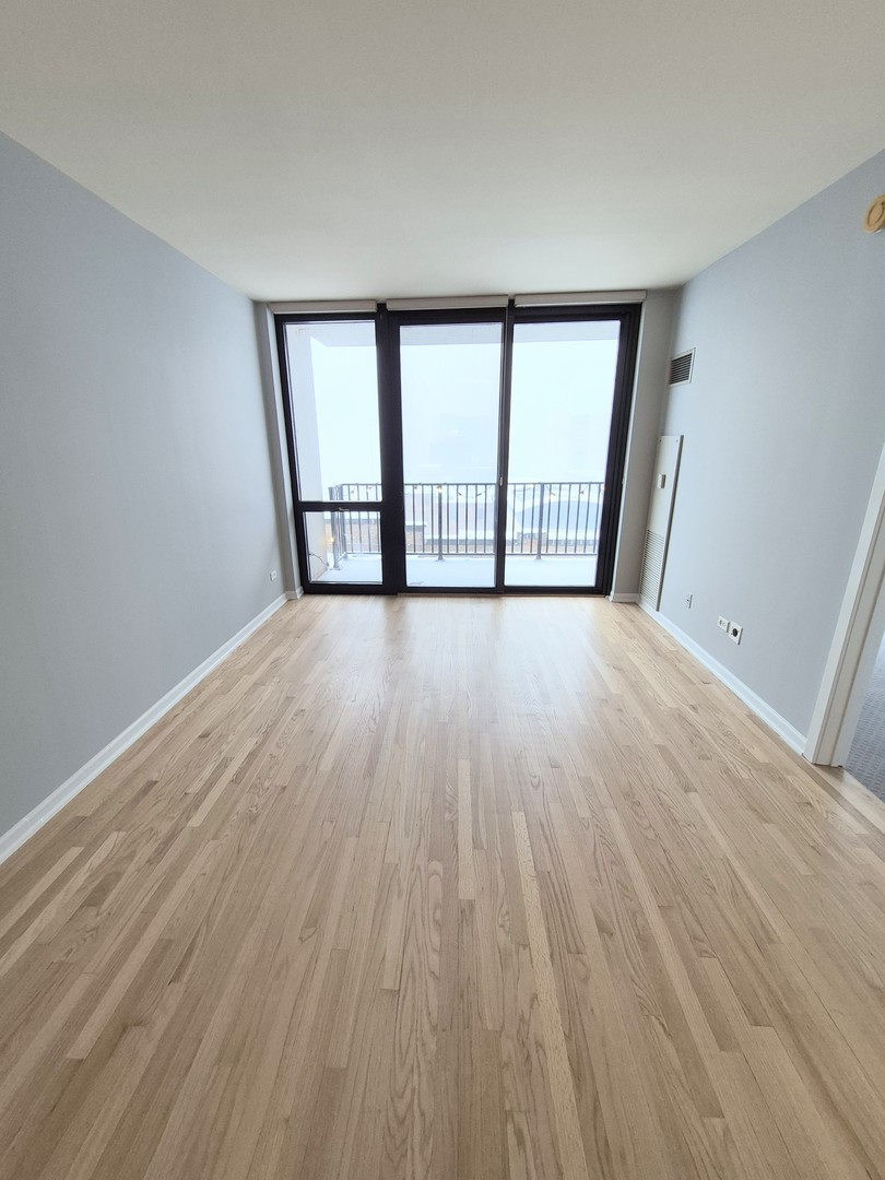 210 South Desplaines Street, Unit 707 Chicago, IL 60661 - Photo 12 of 21 wooden floor in an empty room with a window