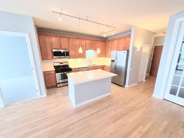 a large white kitchen with wooden floor and stainless steel appliances