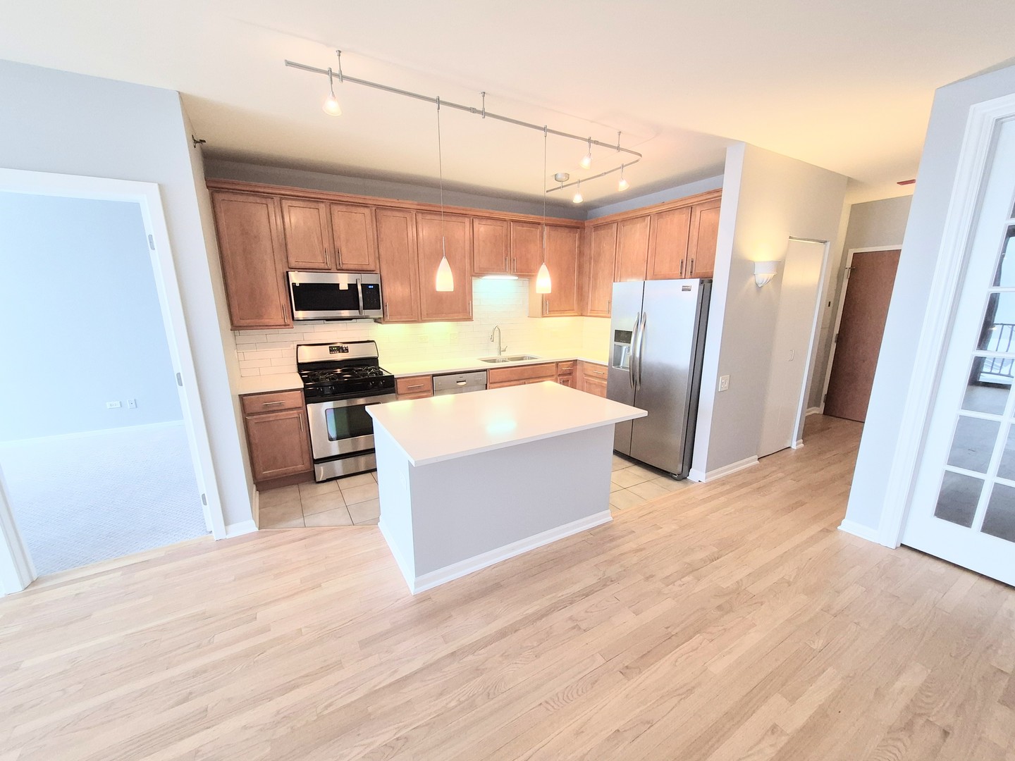 210 South Desplaines Street, Unit 707 Chicago, IL 60661 - Photo 3 of 21 a large white kitchen with wooden floor and stainless steel appliances