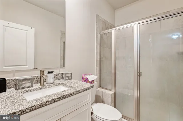 a bathroom with a granite countertop sink toilet mirror and shower