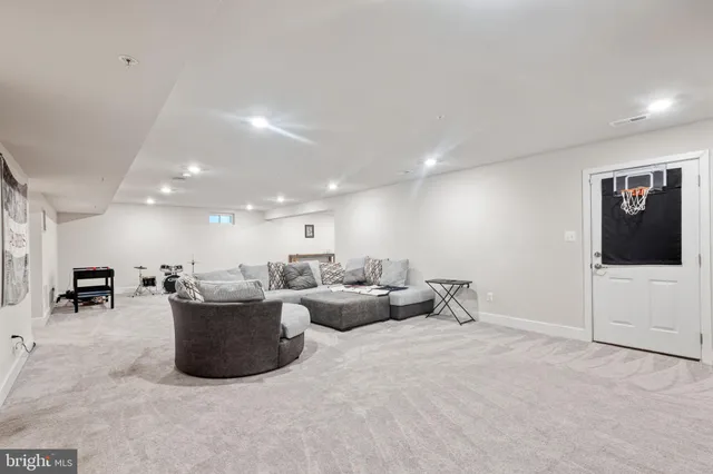 a living room with furniture a flat screen tv and a refrigerator