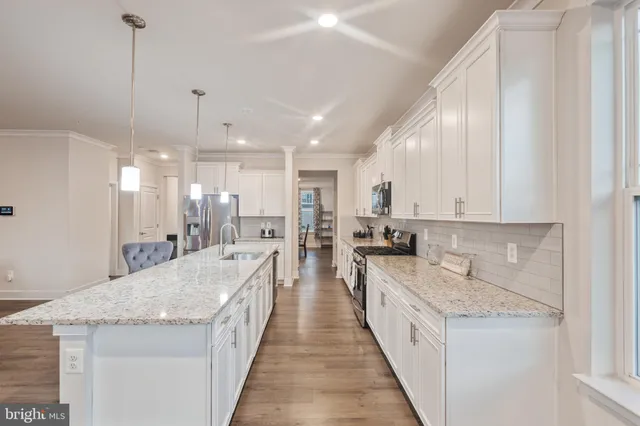 a large white kitchen with granite countertop lots of counter space and stainless steel appliances