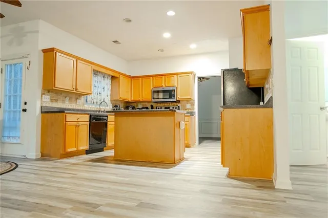 a kitchen with stainless steel appliances granite countertop a refrigerator a stove and a microwave