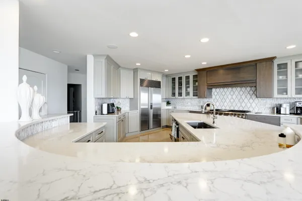 a view of a kitchen with kitchen island a large counter top stainless steel appliances and cabinets