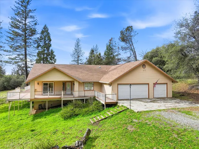 a view of a big house with a big yard and large trees