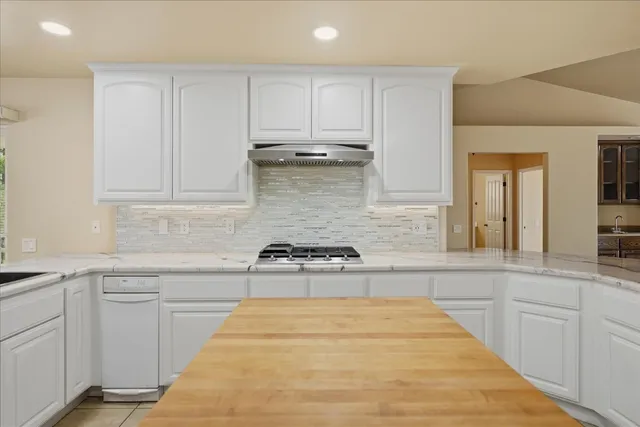 a kitchen with stainless steel appliances granite countertop a refrigerator and a stove top oven
