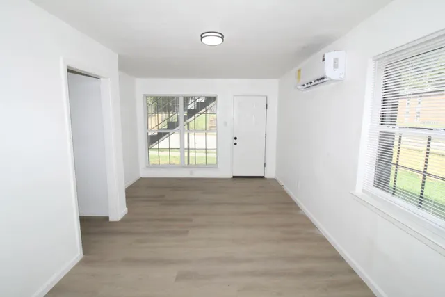 a view of an empty room with wooden floor and a window
