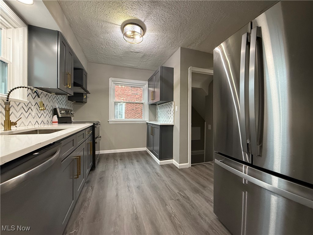 6807 Gerald Avenue Parma, OH 44129 - Photo 6 of 25 Kitchen featuring gray cabinetry, decorative backsplash, light countertops, a sink, and appliances with stainless steel finishes