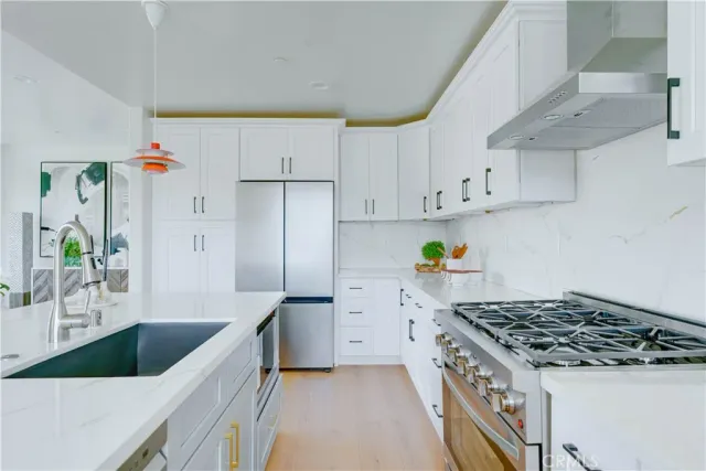a kitchen with stainless steel appliances granite countertop a stove a refrigerator and a white cabinets