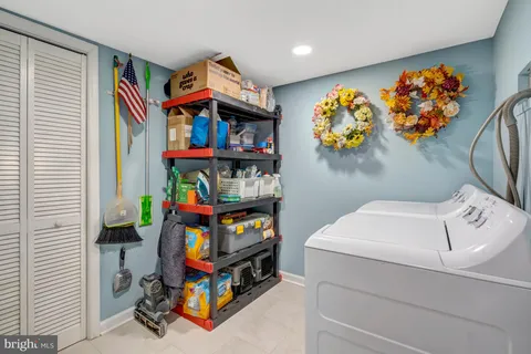 a utility room with fridge dryer and book shelf