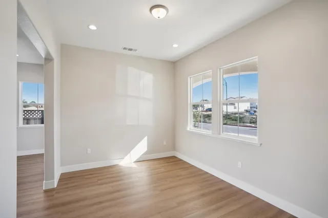 an empty room with wooden floor and a kitchen