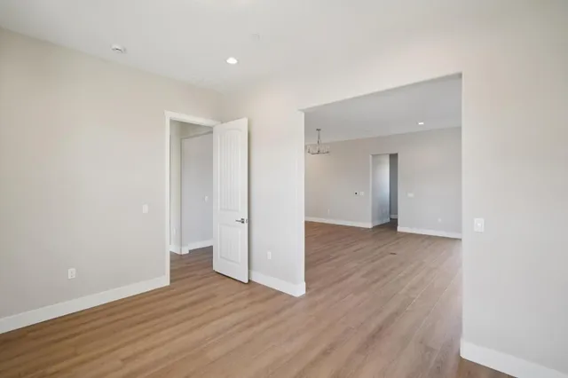 a view of kitchen and empty room with wooden floor