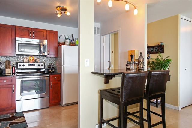 5445 North Sheridan Road, Unit 3904 Chicago, IL 60640 - Photo 4 of 8 a kitchen with stainless steel appliances kitchen island granite countertop a refrigerator and a stove top oven