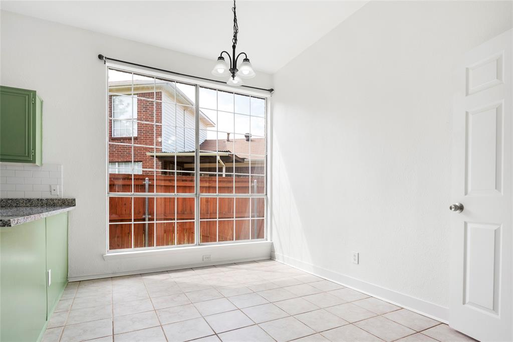 559 Raintree Circle Coppell, TX 75019 - Photo 16 of 40 Spacious room featuring a large picture window, a black chandelier, tile flooring, sage green lower cabinetry, and a light-toned countertop with a white subway tile backsplash