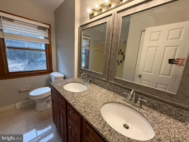 a bathroom with a granite countertop double vanity sink and a mirror